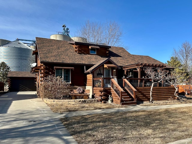 cabin featuring a garage, roof with shingles, log siding, and a pergola