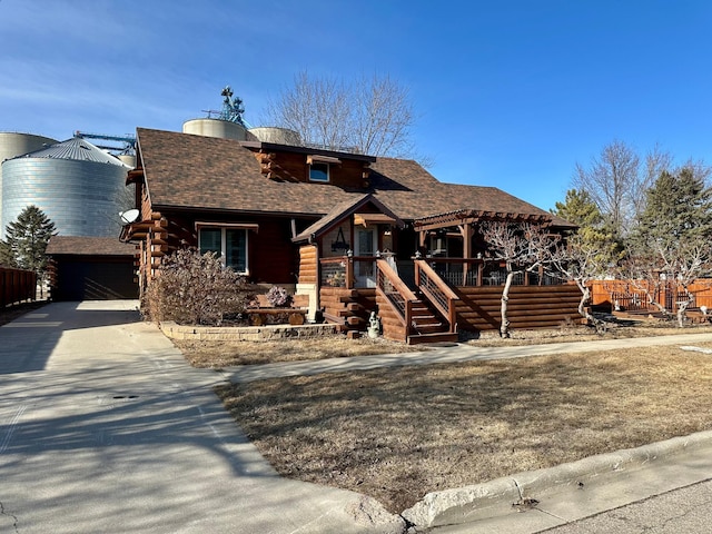 cabin featuring a pergola and roof with shingles