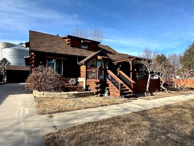 log home with a shingled roof and driveway