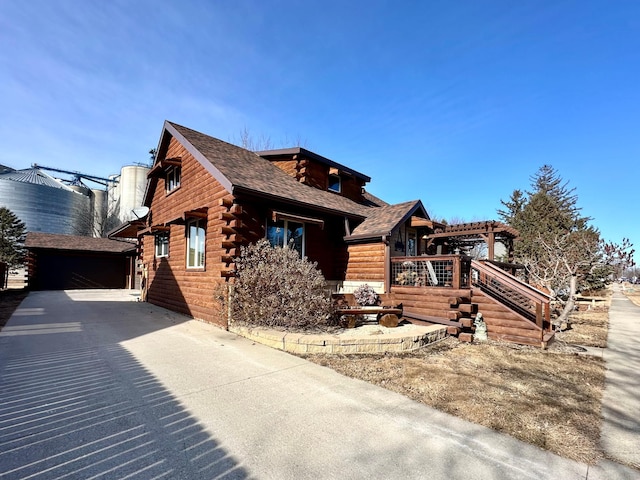 log cabin featuring a shingled roof and log exterior