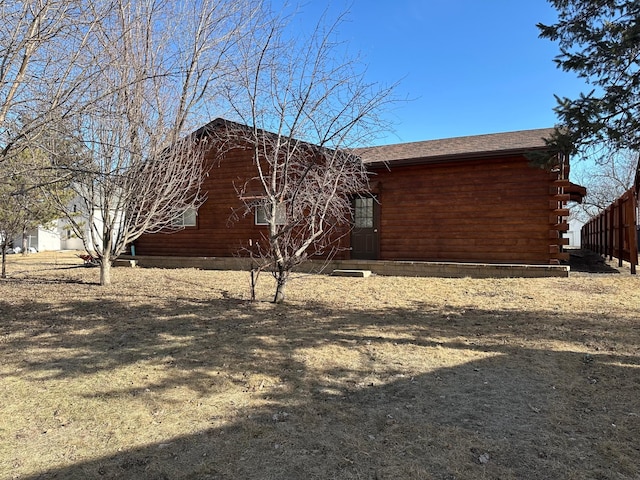 view of home's exterior featuring fence and log exterior