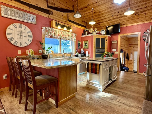 kitchen with wooden ceiling, light wood-style flooring, freestanding refrigerator, light stone countertops, and vaulted ceiling