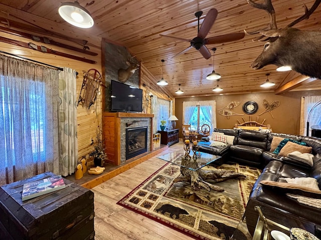 living room with wood ceiling, vaulted ceiling, wood finished floors, and a stone fireplace