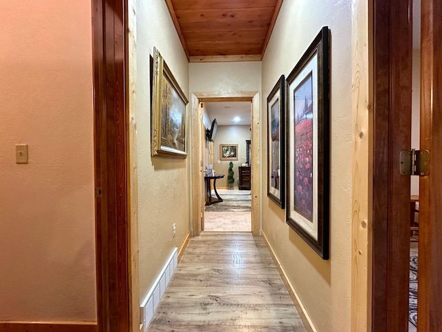 hallway with wood ceiling, light wood-type flooring, visible vents, and baseboards