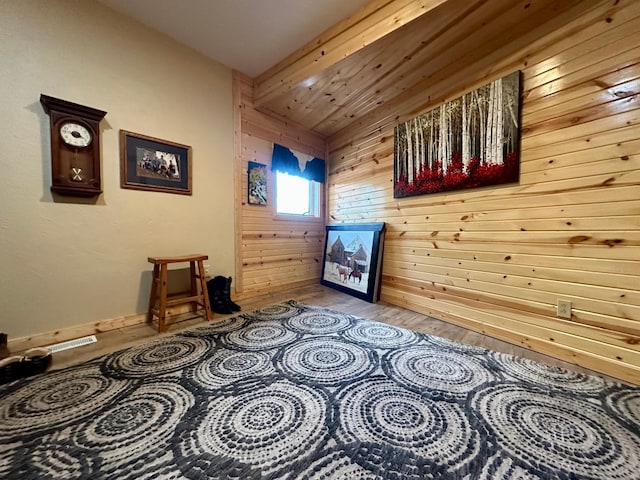 interior space with beam ceiling, wood walls, and wood finished floors