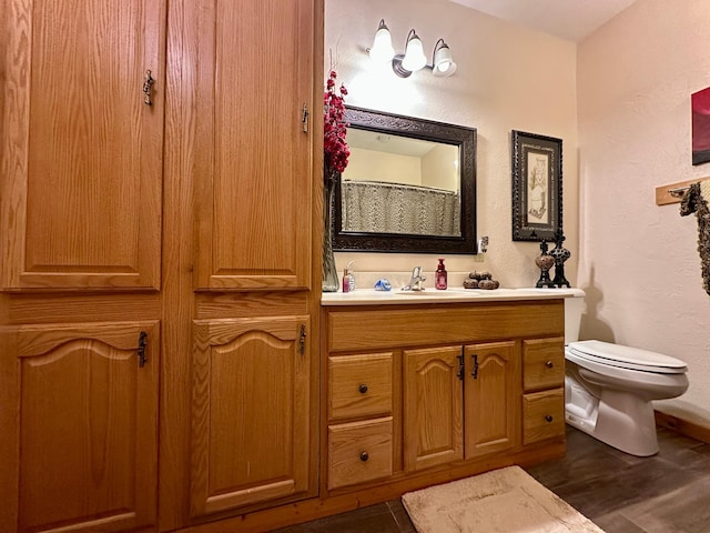 bathroom featuring a textured wall, vanity, toilet, and wood finished floors