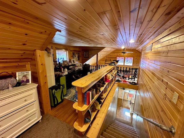 interior space featuring lofted ceiling, visible vents, wood walls, and wood finished floors