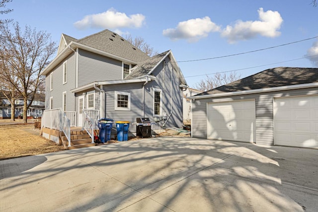 rear view of property featuring a shingled roof and an outdoor structure