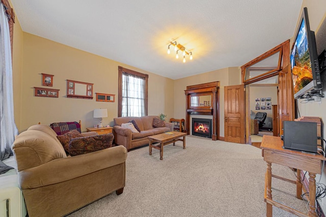 carpeted living room with a textured ceiling and a glass covered fireplace