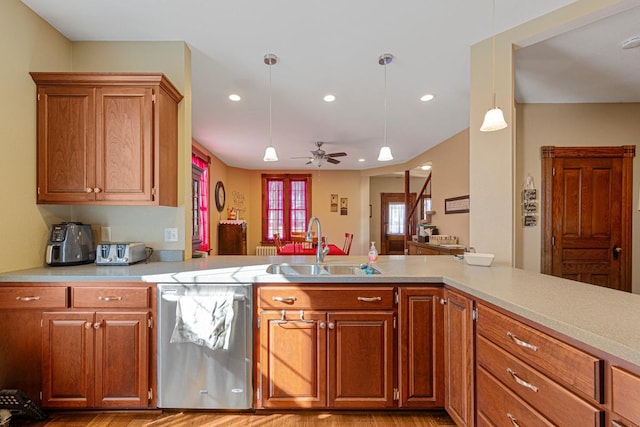 kitchen with brown cabinets, light countertops, a sink, and stainless steel dishwasher