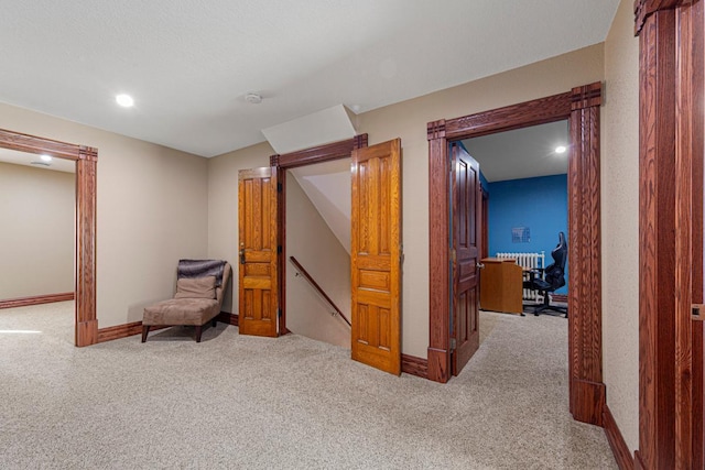 hallway with carpet, baseboards, and an upstairs landing