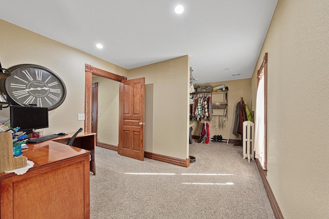 carpeted office space featuring recessed lighting, baseboards, a textured wall, and radiator heating unit