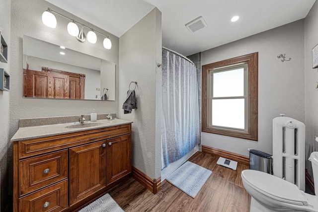 bathroom featuring visible vents, toilet, vanity, wood finished floors, and baseboards