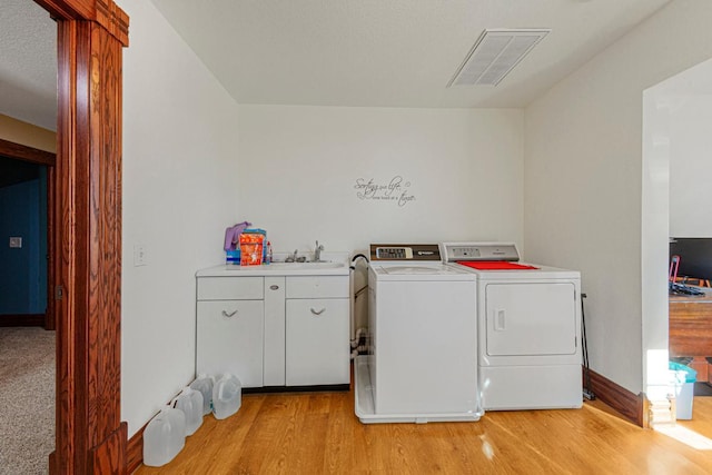 laundry area with cabinet space, light wood finished floors, baseboards, visible vents, and separate washer and dryer