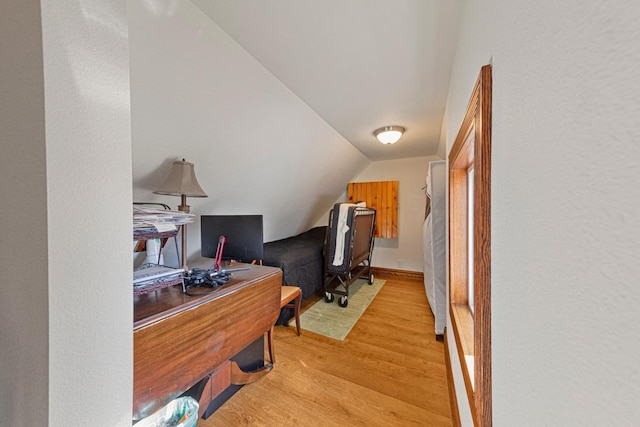 home office with vaulted ceiling, baseboards, and light wood-style floors