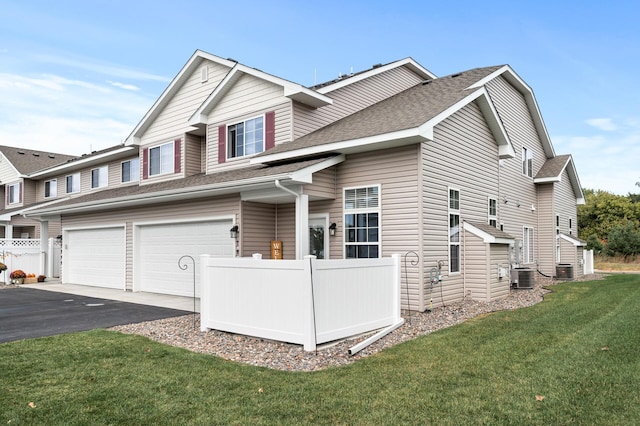 exterior space with aphalt driveway, roof with shingles, central AC unit, fence, and a front lawn