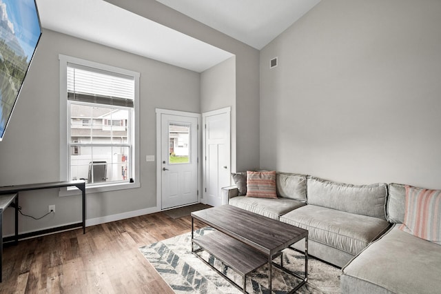 living room featuring lofted ceiling, wood finished floors, visible vents, and baseboards