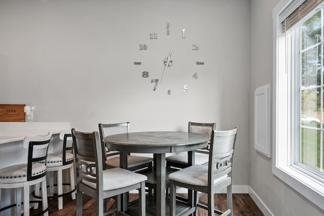 dining area with baseboards and dark wood-type flooring