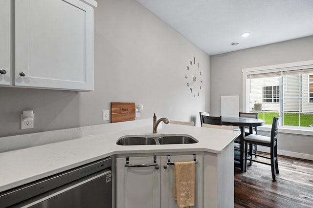 kitchen featuring a peninsula, dark wood-style flooring, a sink, light countertops, and stainless steel dishwasher