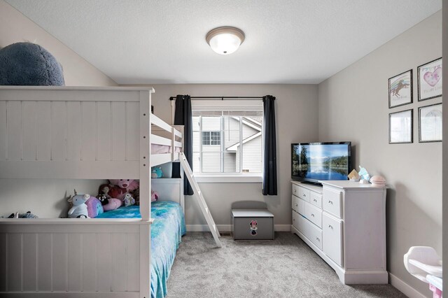 bedroom with baseboards, a textured ceiling, and light colored carpet