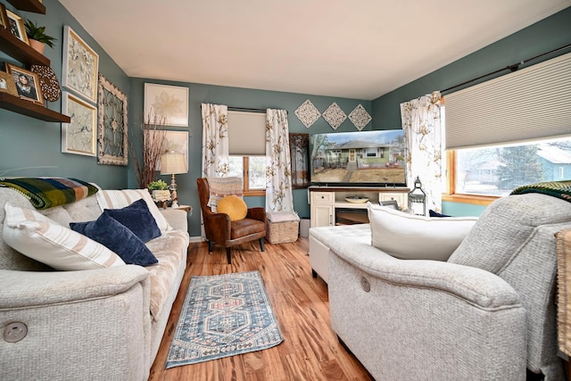 living room featuring baseboards, wood finished floors, and a healthy amount of sunlight