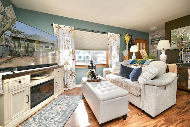 living room featuring wood finished floors and a glass covered fireplace