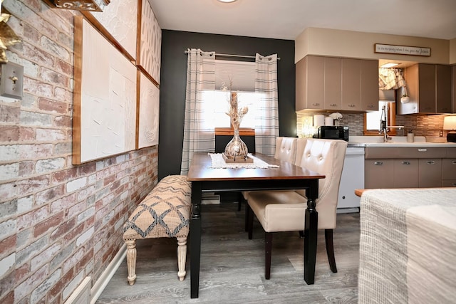 dining room with brick wall and wood finished floors