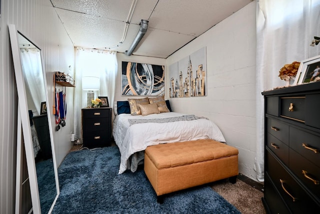 carpeted bedroom with concrete block wall