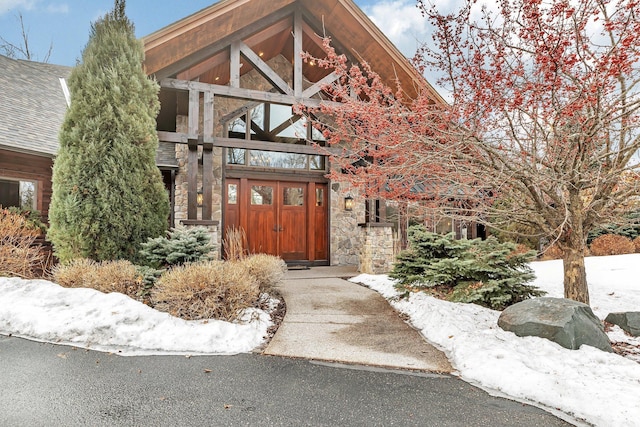 property entrance with stone siding and a shingled roof