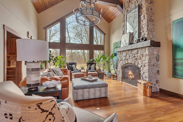 living area featuring high vaulted ceiling, a stone fireplace, wood finished floors, a chandelier, and wooden ceiling