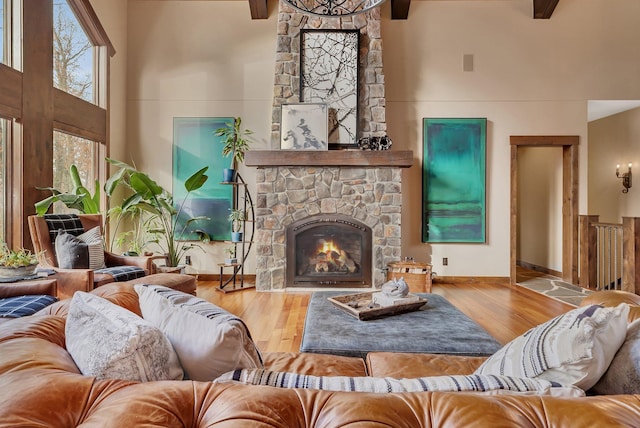 living area featuring a high ceiling, wood finished floors, and a stone fireplace