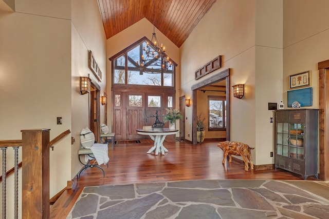 foyer entrance with baseboards, wood ceiling, wood finished floors, high vaulted ceiling, and a notable chandelier