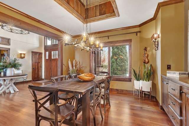 dining room with light wood-type flooring, an inviting chandelier, baseboards, and ornamental molding