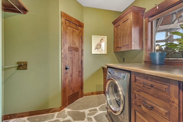 washroom featuring cabinet space, baseboards, and washer / clothes dryer