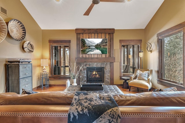 living area featuring lofted ceiling, a stone fireplace, and wood finished floors