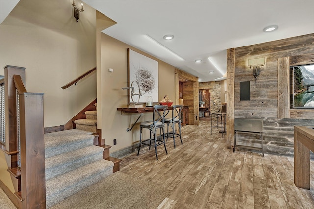 bar featuring recessed lighting, wood finished floors, baseboards, and stairs