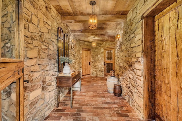 hallway with brick floor, wooden ceiling, and beam ceiling