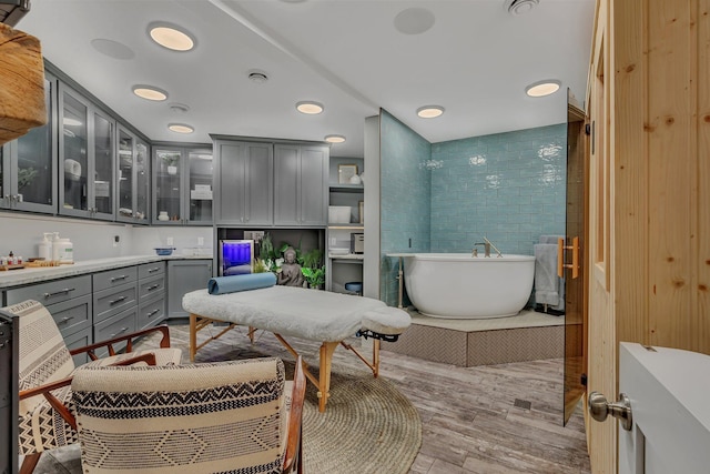 full bathroom with a freestanding tub, vanity, and wood finished floors