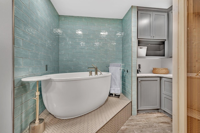 bathroom with a freestanding bath, vanity, and tile walls