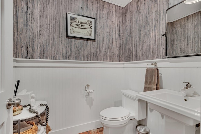 bathroom featuring a wainscoted wall, a sink, and toilet