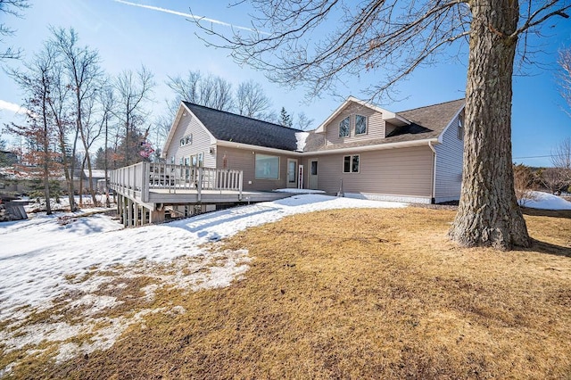 snow covered rear of property with a yard and a deck