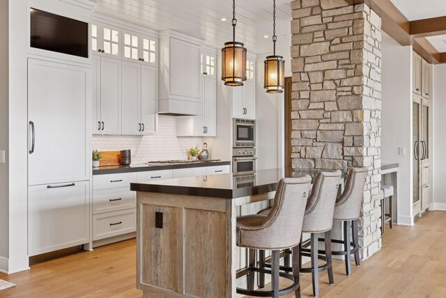 875 Lake St N Unit 402, Wayzata, MN 55391 - kitchen with appliances with stainless steel finishes, dark countertops, light wood-type flooring, backsplash, and white cabinetry