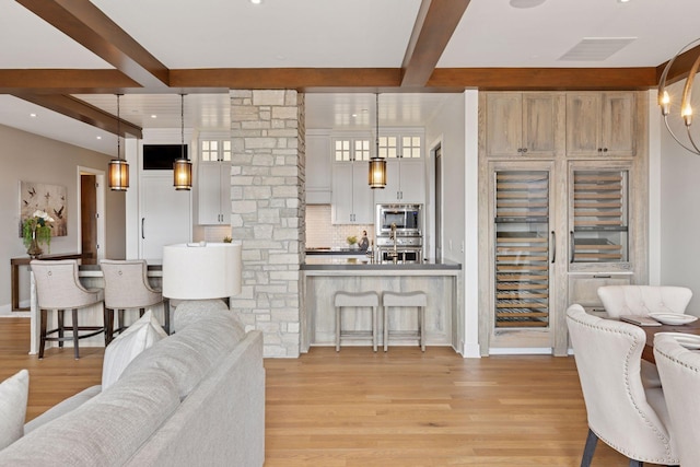 875 Lake St N Unit 402, Wayzata, MN 55391 - living area with beverage cooler, visible vents, decorative columns, light wood-style floors, and beam ceiling
