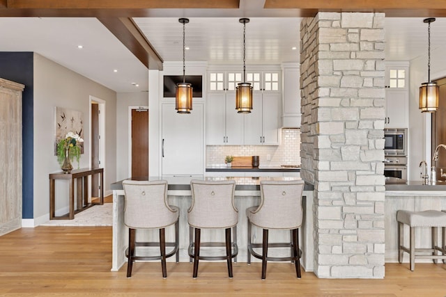 875 Lake St N Unit 402, Wayzata, MN 55391 - kitchen with stainless steel appliances, decorative backsplash, a breakfast bar, white cabinets, and glass insert cabinets