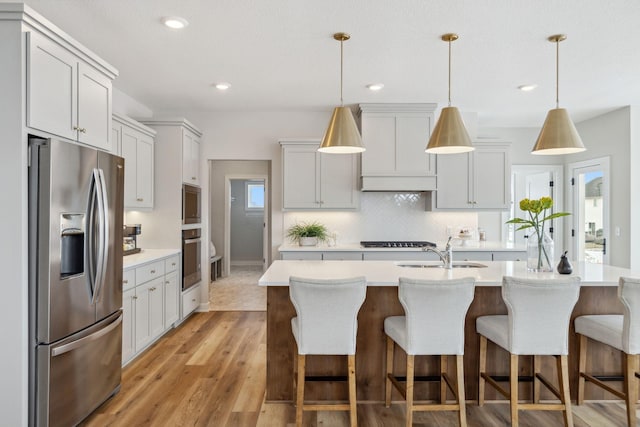 kitchen featuring a sink, light countertops, tasteful backsplash, black stovetop, and stainless steel fridge