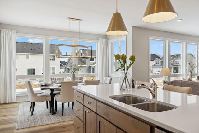 kitchen with light wood finished floors, light countertops, a sink, and decorative light fixtures