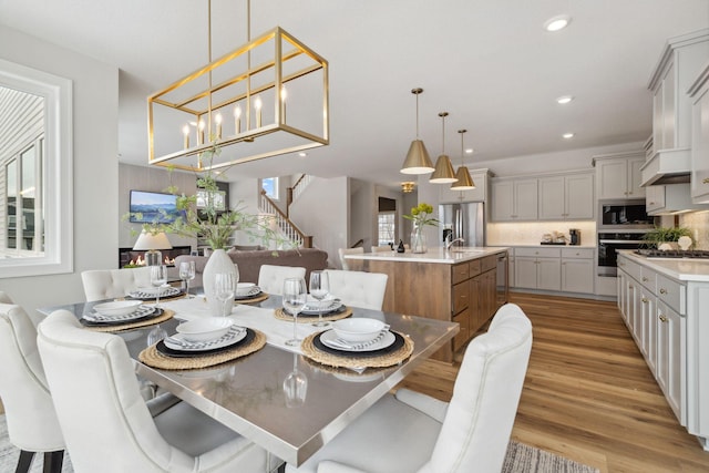 dining room featuring recessed lighting, light wood finished floors, and stairs