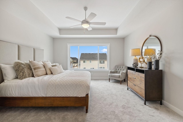 bedroom with a raised ceiling, light carpet, ceiling fan, and baseboards