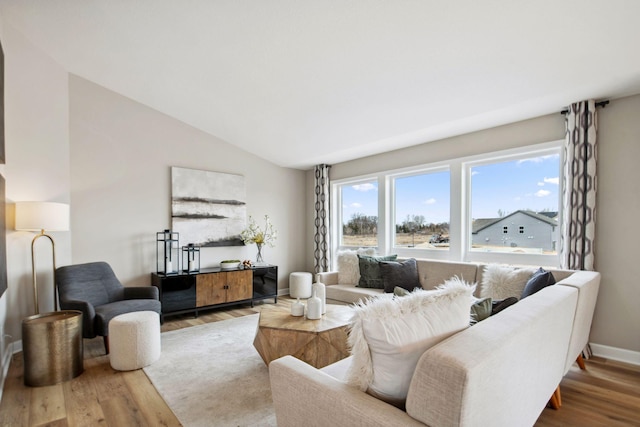 living area featuring lofted ceiling, wood finished floors, and baseboards