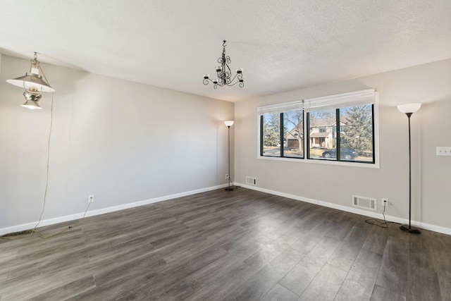 unfurnished room featuring baseboards, a textured ceiling, visible vents, and wood finished floors